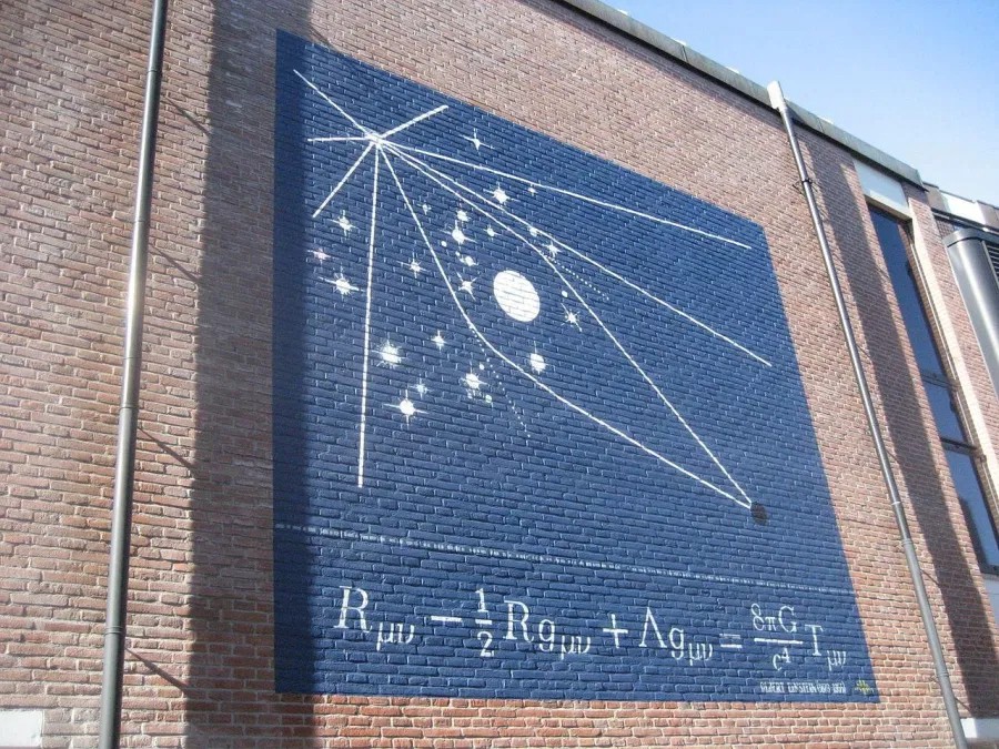 A mural of the Einstein field equations, with an illustration of light bending around the eclipsed sun, the observations that first validated general relativity back in 1919. The Einstein tensor is shown decomposed, at left, into the Ricci tensor and Ricci scalar. (Credit: Vysotsky / Wikimedia Commons)